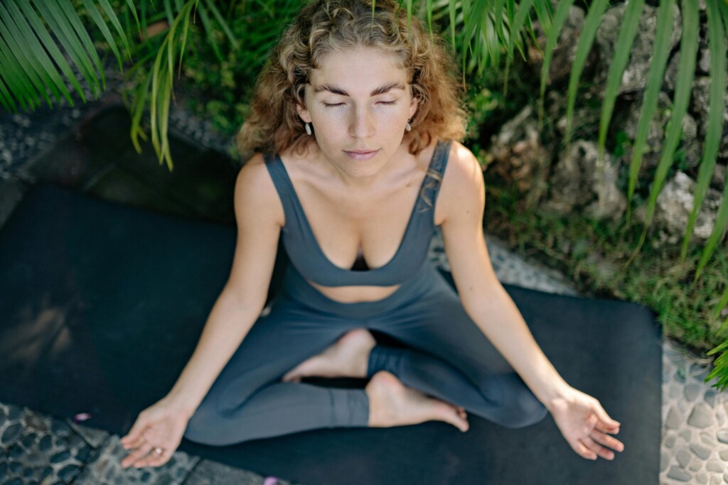 a person meditating in butterfly pose—hands resting on knees, eyes closed
